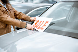salesperson-putting-sale-sign-car